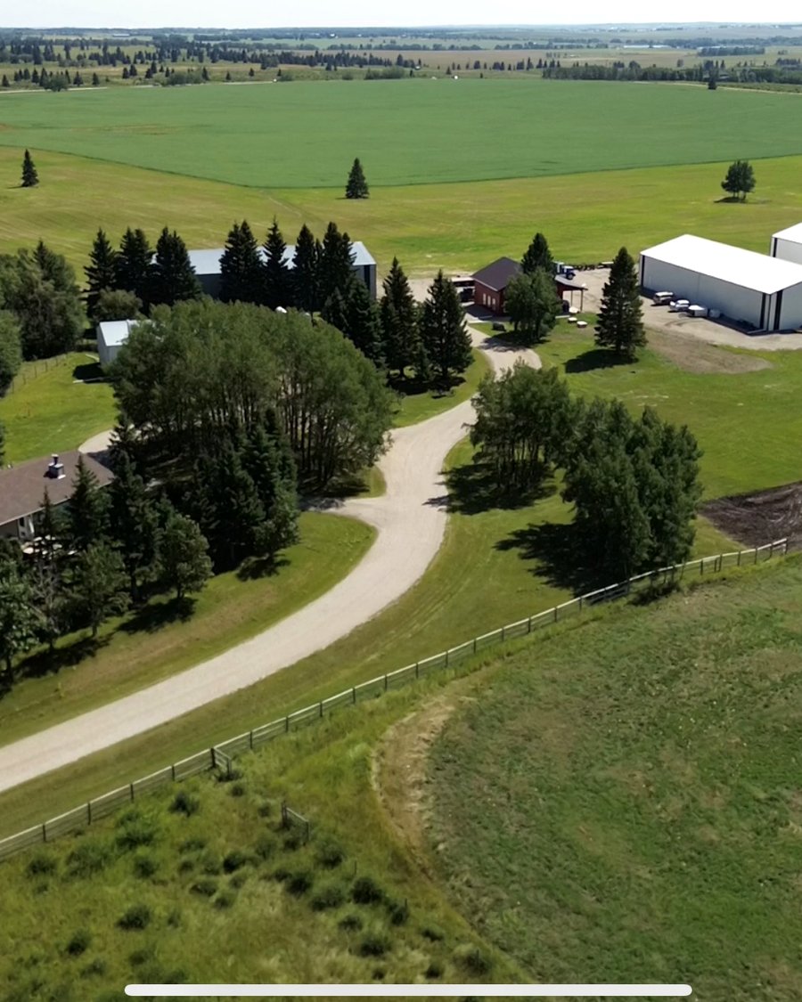 Wide aerial view of a rural acreage property with outbuildings and hangars near Calgary
